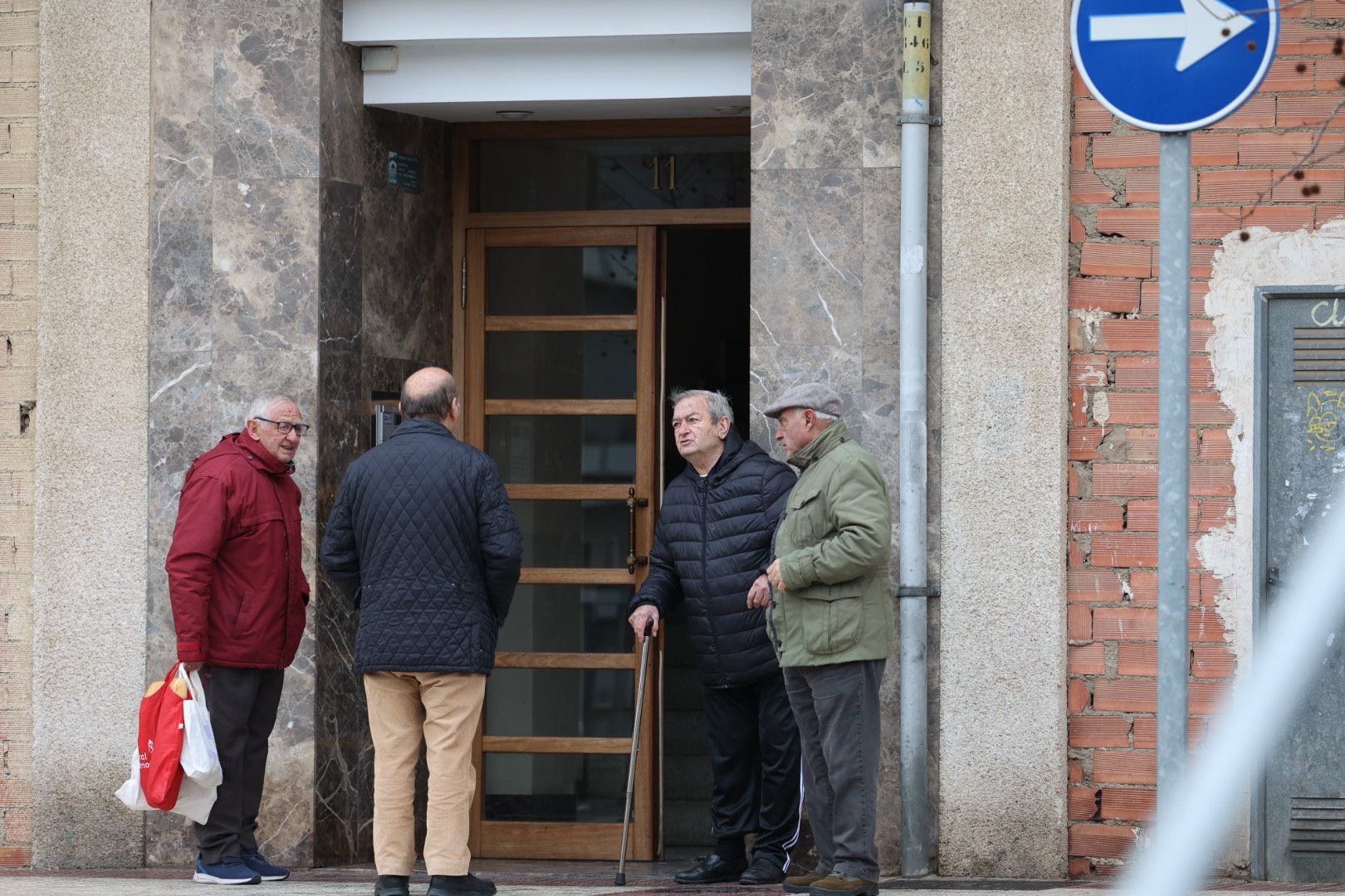 Un grupo de personas charla junto al portal en el que se encuentra el piso donde se originó el fuego.