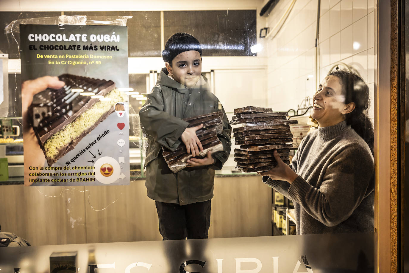 Pacientes como Abraham, que posa con el chocolate en la pastelería Damasco, deben viajar periódicamente hasta San Sebastián, con escasa ayuda, para revisar sus implantes cocleares.