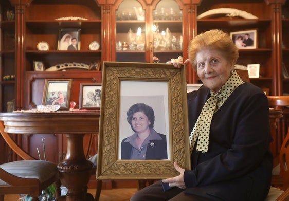 Angelines posa en el salón de su casa sosteniendo una fotografía en la época que ejercía su profesión.