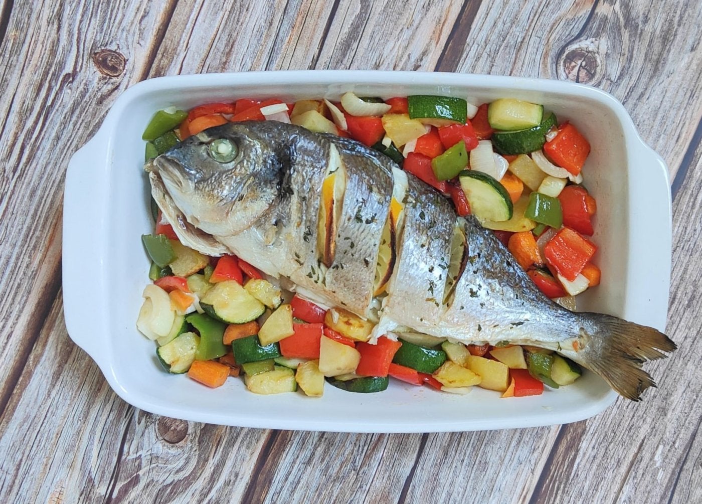 Dorada al horno sobre cama de verduras.