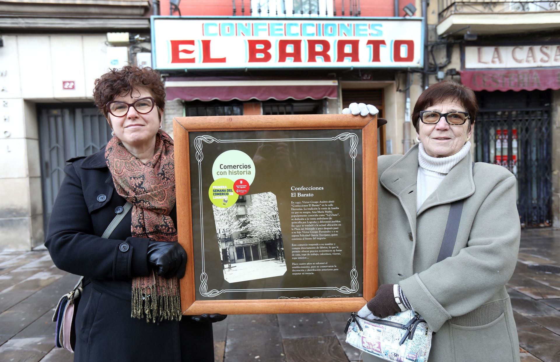 Madre e hija, con el cuadro en reconocimiento a la condición de «comercio con historia» del de la plaza del Mercado 23.