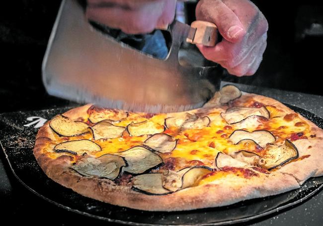 Corte de una pizza recién horneada.