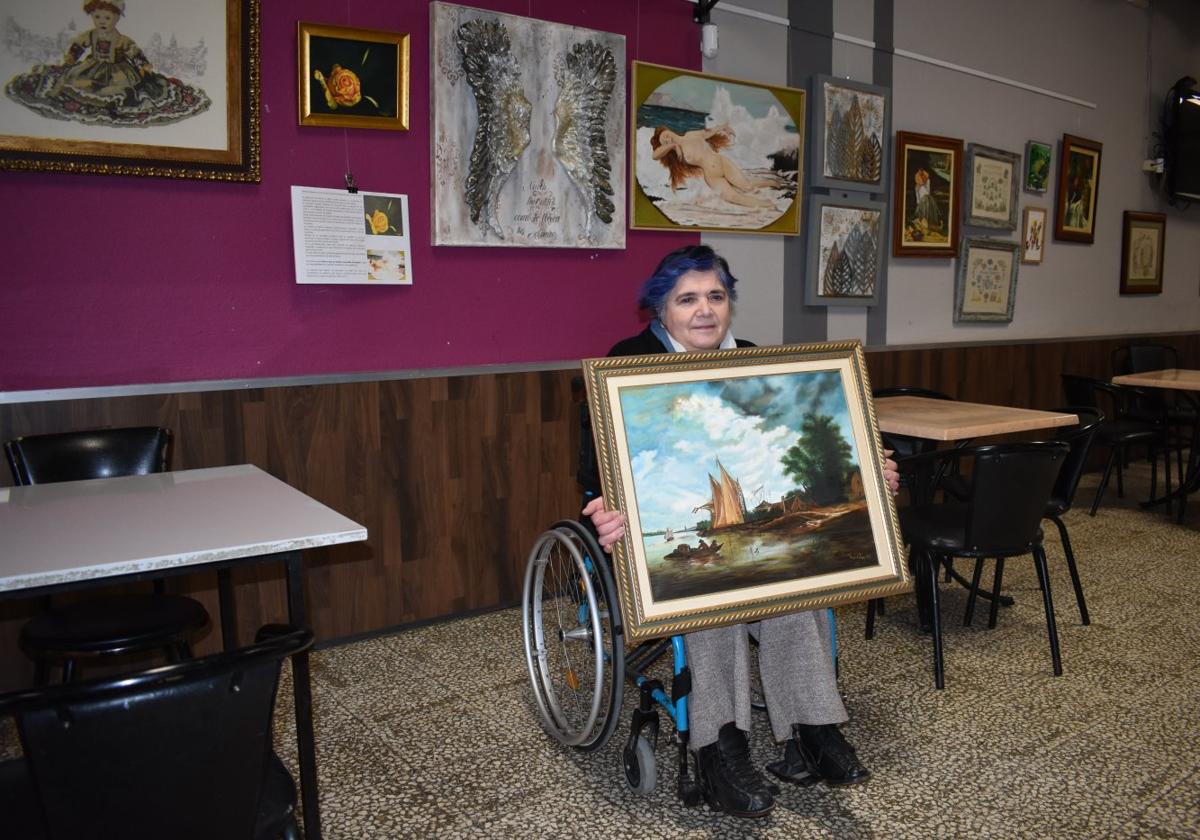 Mariluz Matute con un cuadro de estilo holandés pintado por ella, delante de otras obras de la muestra.