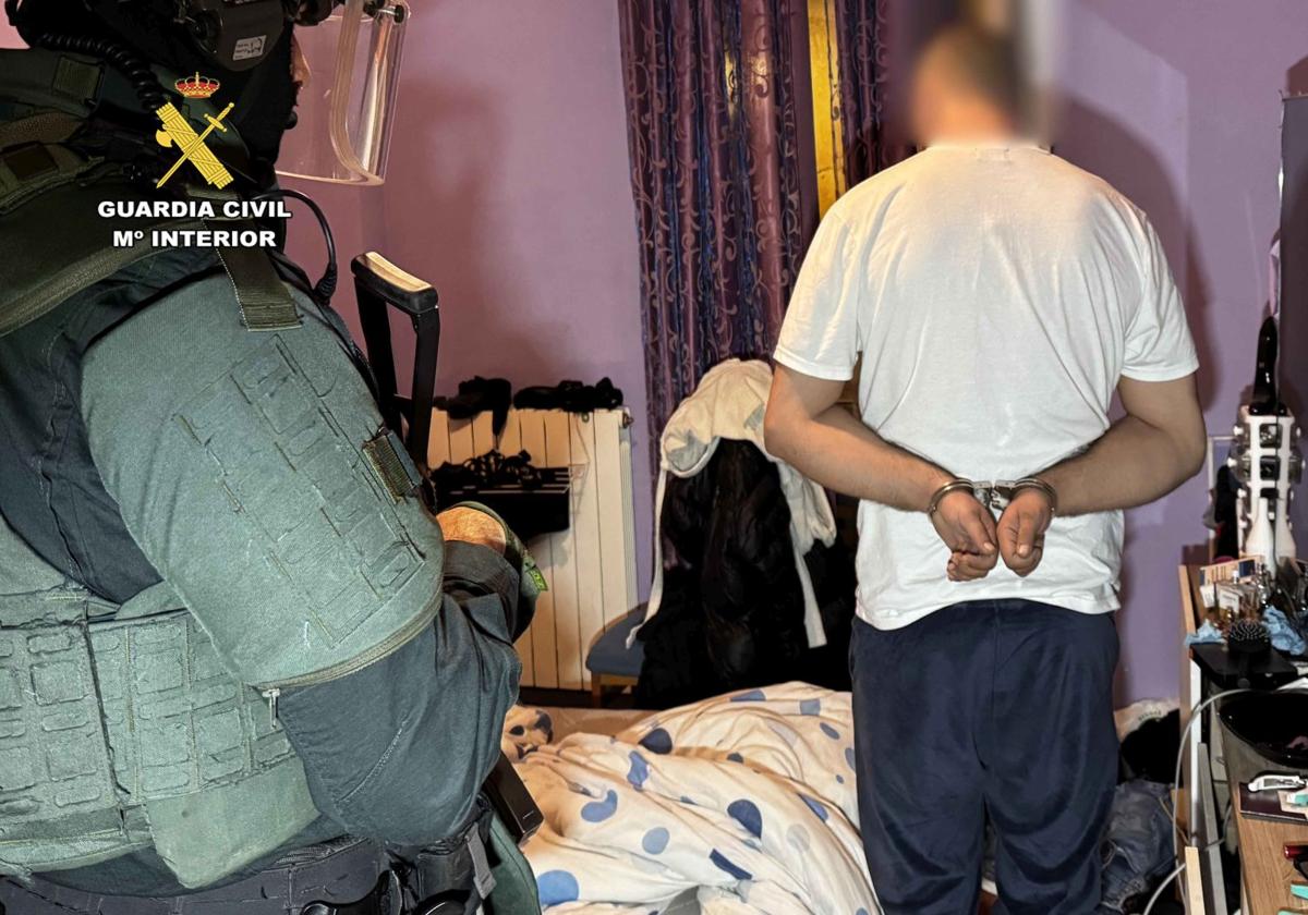 Uno de los detenidos, durante el registro en la vivienda de los presuntos autores.
