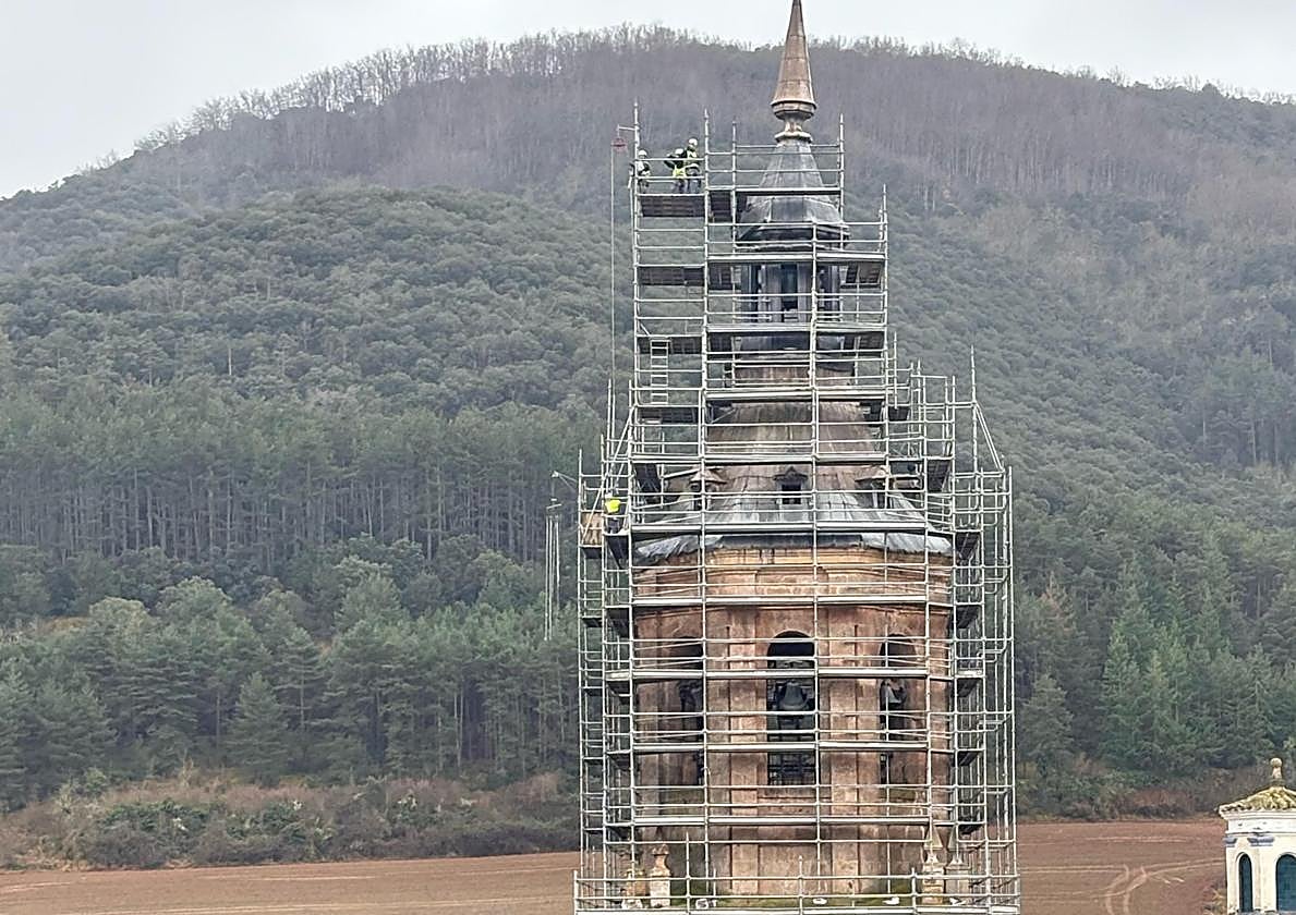 Los obreros, apenas pequeñas motas, terminan de apuntalar la estructura de metal alrededor de la torre.