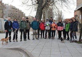 Los quince participantes posan antes de comenzar a andar, algunos con bastones, otros con perros, en las inmediaciones de la estación de autobuses de Nájera.