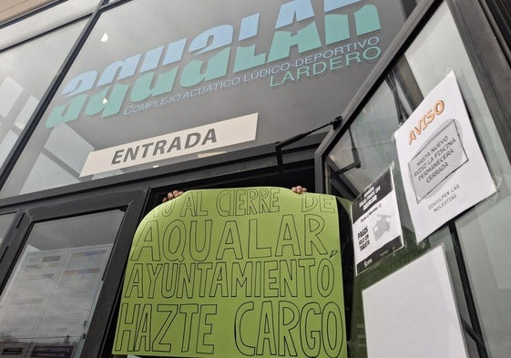 Un miembro del personal de Aqualar muestra un cartel de protesta en la entrada.