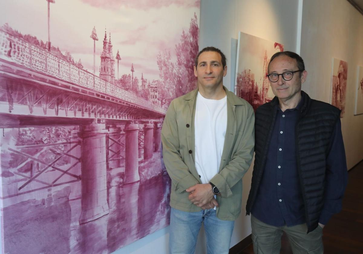 Larry Karlin y Carlos López Garrido en su exposición, junto al lienzo sobre el Puente de Hierro de Logroño.