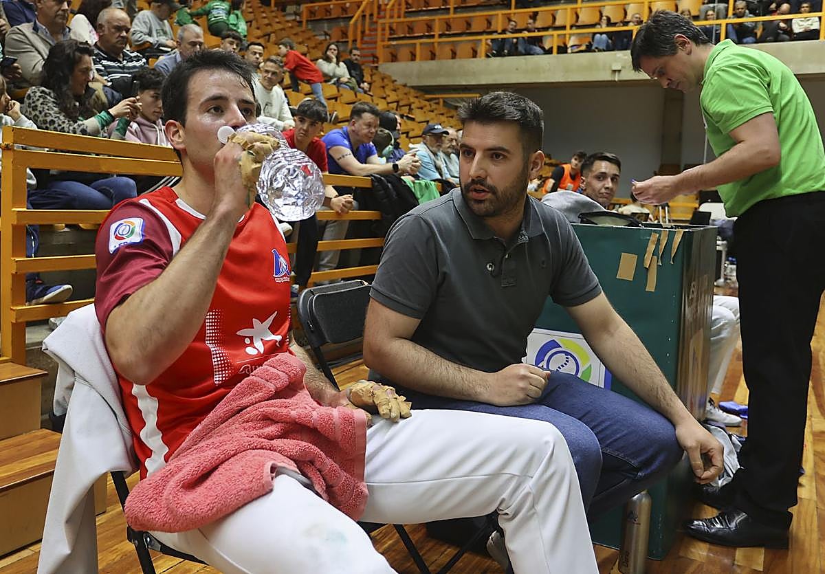 Darío Gómez bebe agua en la silla mientras escucha a su hermano Asier, durante el primer partido contra Zabala.