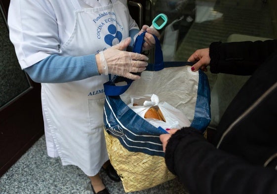 Una usuaria de la Cocina Económica recoge comida en una bolsa, en una imagen de archivo.