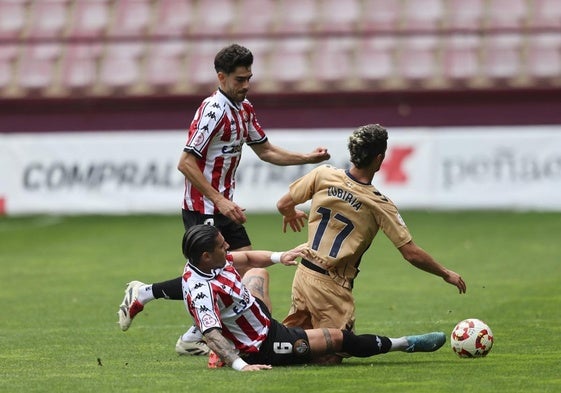 Lamadrid y Castañeda, desde el suelo, intentan arrebatarle el balón a Zubiria, del Eibar B.