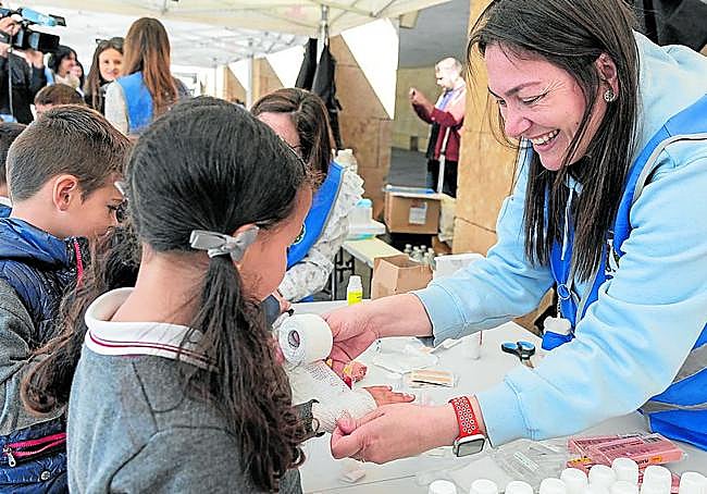 Una enfermera muestra a varios niños como se realiza un vendaje en una muñeca.
