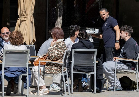 Un camarero atiende a un grupo de jóvenes sentados en una terraza en la plaza del Mercado, en Logroño.