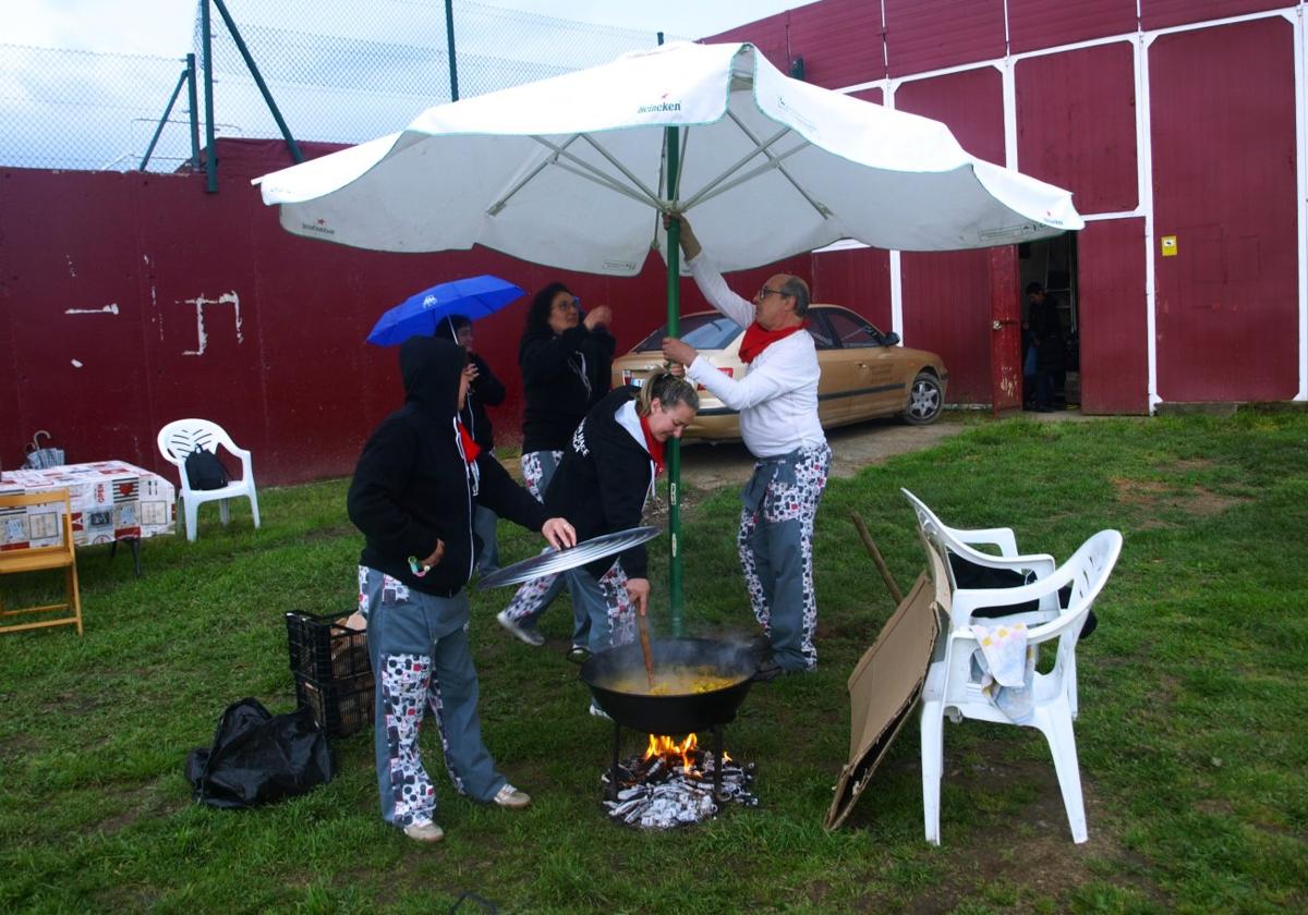 Una cuadrilla abría una sombrilla para proteger la paella del agua.