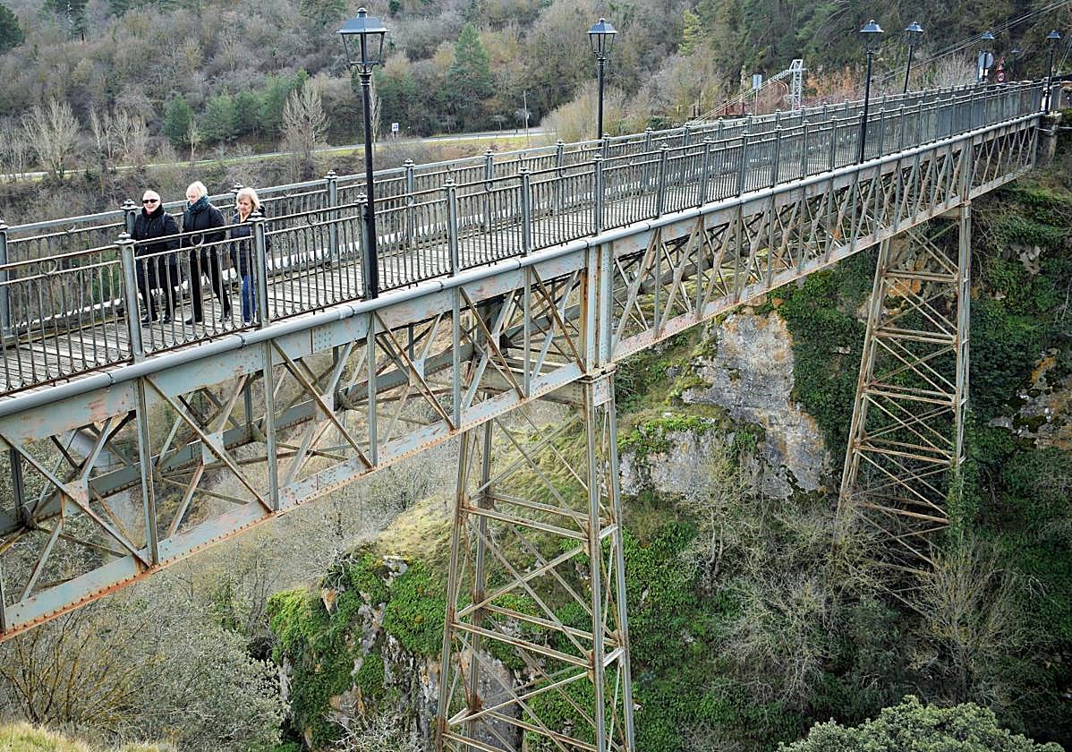 Tres vecinas de Ortigosa cruzan el puente de hierro.