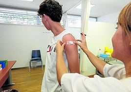 Una enfermera coloca una tirita a un joven tras administrarle la vacuna frente al virus del papiloma humano.