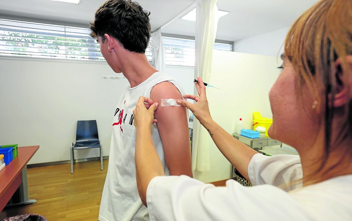 Una enfermera coloca una tirita a un joven tras administrarle la vacuna frente al virus del papiloma humano.