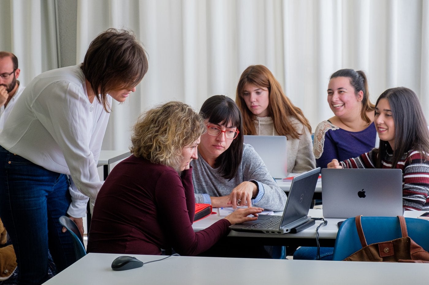 Una profesora observa la evolución del trabajo grupal de sus estudiantes.
