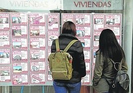 Dos mujeres consultan los anuncios de una inmobiaria.