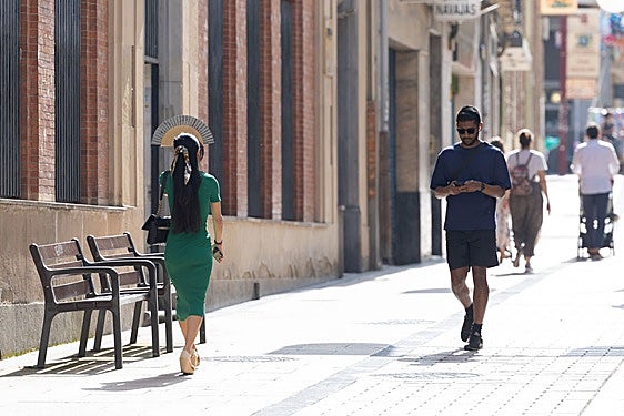 Una mujer se protege del sol con un abanico en la calle portales de Logroño.
