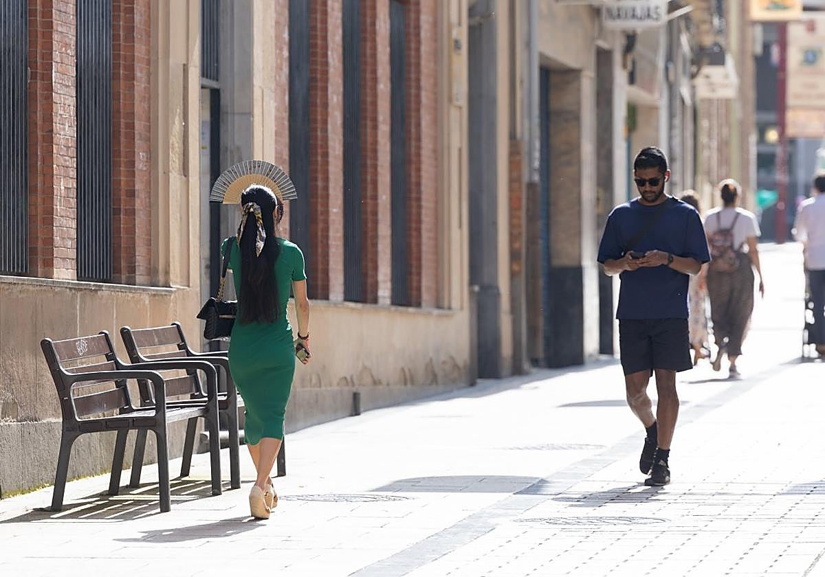 Una mujer se protege del sol con un abanico en la calle Portales de Logroño.