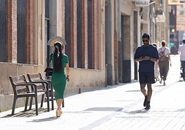 Una mujer se protege del sol con un abanico en la calle Portales de Logroño.