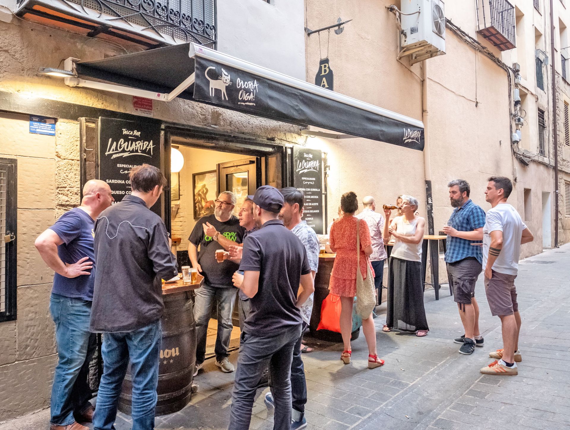 Personas bebiendo y comiendo en uno de los bares de la calle San Juan.