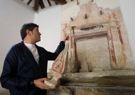 Pedro Muro, alcalde de Clavijo, señala el retablo oculto que ha sido descubierto en la ermita de San Román mientras porta en la mano una parte del retablo barroco que estaba a la vista.