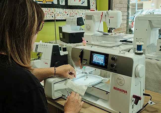 María borda un trozo de tela en su tienda.