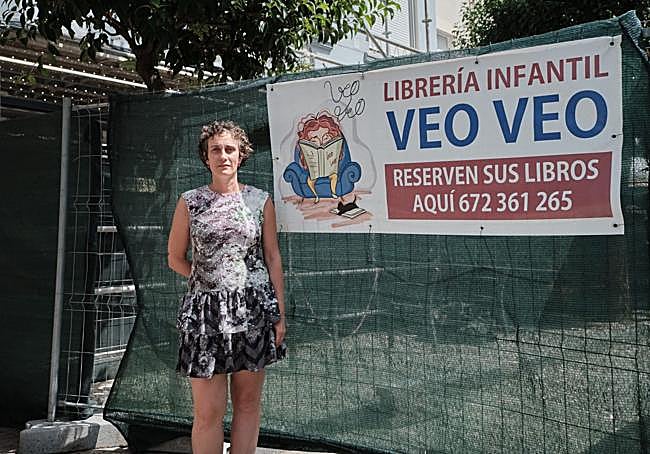 Carmen Mateos posa junto al andamio que invisiviliza su tienda.