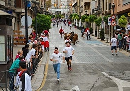 Varios aficionados corren delante de las vacas por la calle Mártires.