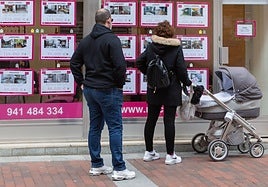 Una pareja mira la oferta de pisos en una inmobiliaria.