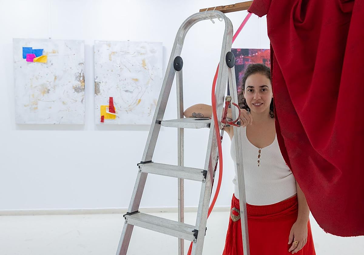 Raquel de la Iglesia junto a la instalación y algunos de los lienzos que expone en Logroño.