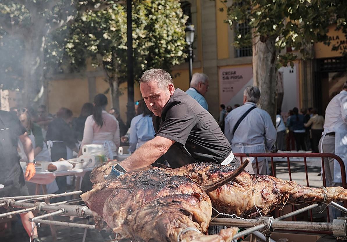 Un hombre corta una ternera ecológica asada en la plaza de la Diversidad.
