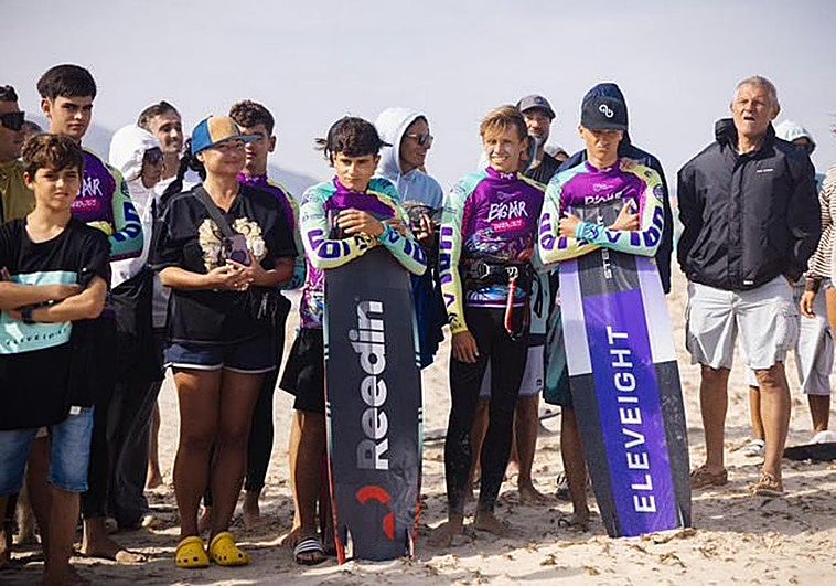 Hugo Renedo, en el medio, posa junto al trofeo de campeón de España júnior de kitesurf en Cádiz.