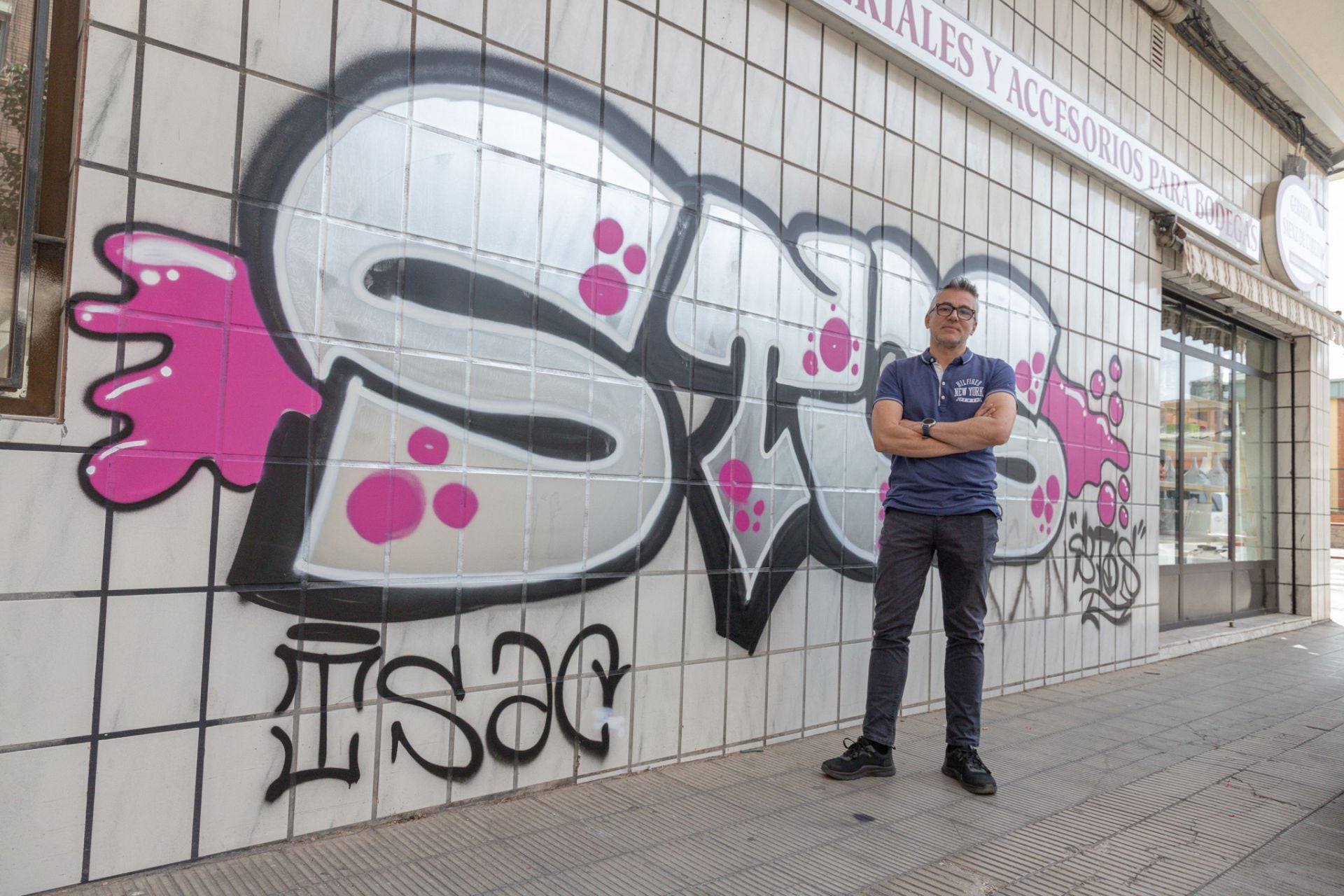 Gerardo Sáenz de Cabezón posa, resignado e impotente, ante la pared pintada de su tienda en la calle Villamediana de Logroño.