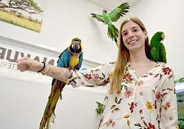 Elena Llop posa con el guacamayo Lora en su mano derecha y el loro Goku en su hombro izquierdo en la clínica veterinaria Nakuru.