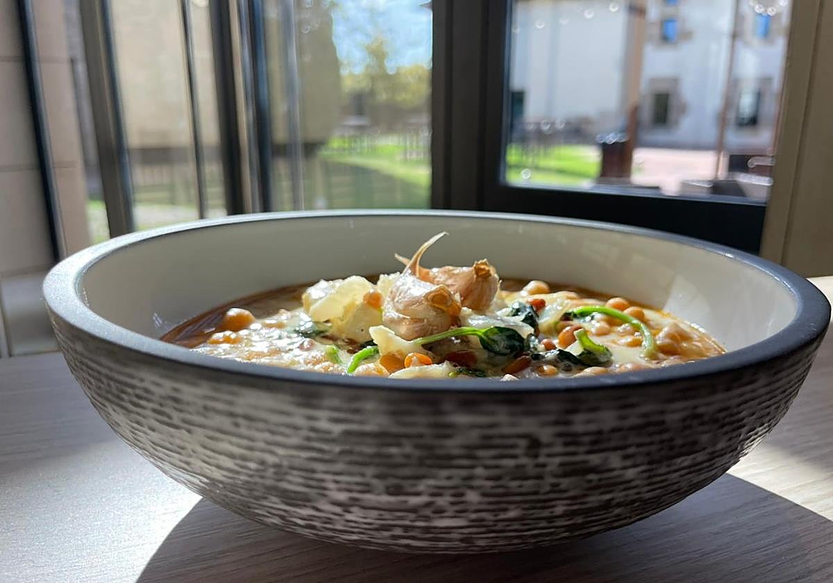 Una ración de garbanzos con espinacas y bacalao, presentados en un plato hondo de diseño.