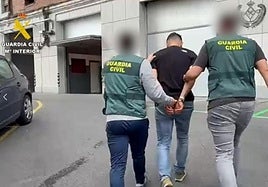 Dos agentes trasladan a uno de los detenidos en la operación.