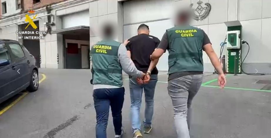 Dos agentes trasladan a uno de los detenidos en la operación.