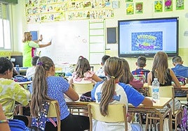 Varios alumnos atienden a su profesora en clase.