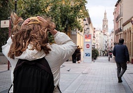 Una mujer se sujeta la gorra para que no se la lleve el viento en Logroño.
