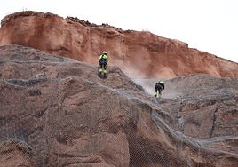 Los operarios avanzan ya la fase de coser a la pared con bulones la malla de triple torsión desplegada en la totalidad de la peña.