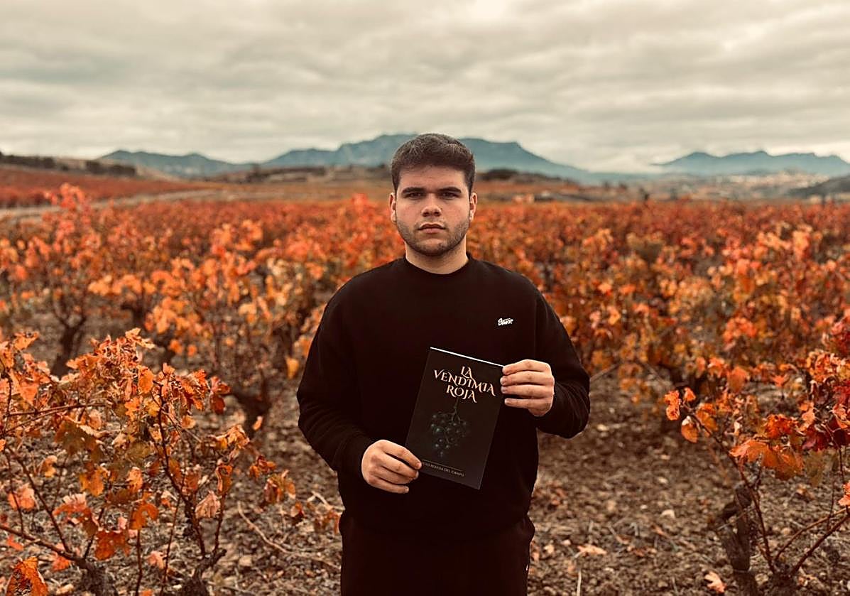 Sergio Pereda con su libro en la mano ante un viñedo otoñal.