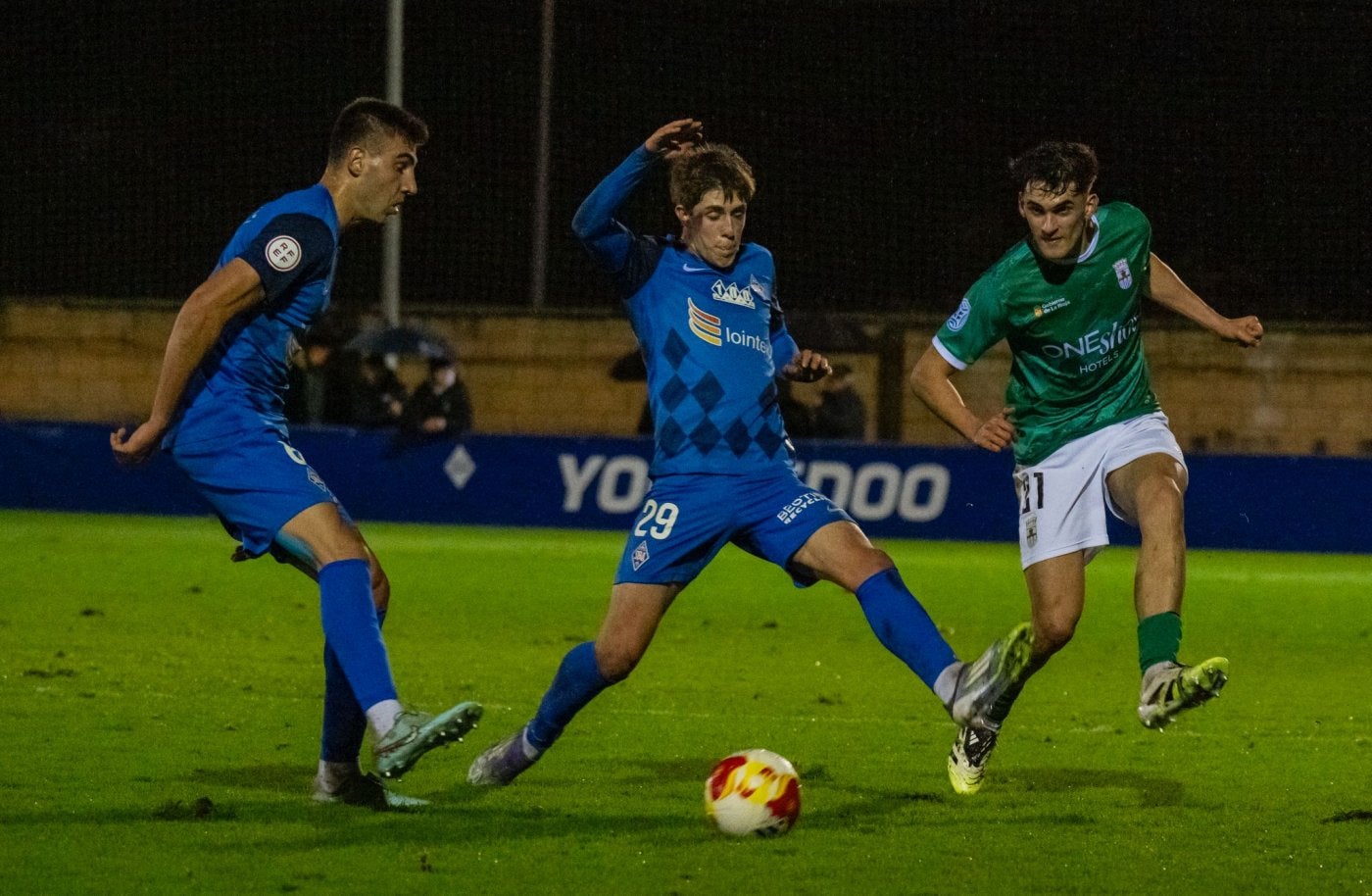 Javier Caño golpea el esférico ante la presión de dos jugadores del Amorebieta.