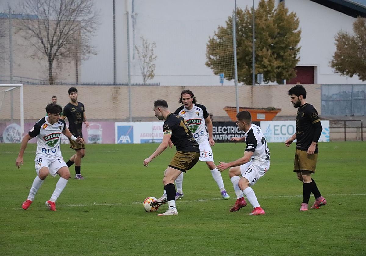 El alfareño Arturo Fernández, uno de los goleadores del pasado domingo, toca entre la defensa del Tudelano y el apoyo de varios compañeros.