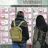 Dos mujeres miran los precios de los pisos en un escaparate.