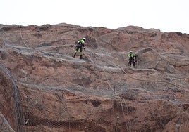 Los operarios trabajando en la malla de la peña, a 80 metros de altura.