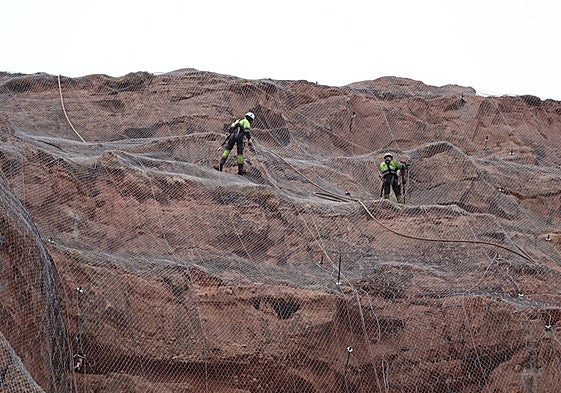 Los operarios trabajando en la malla de la peña, a 80 metros de altura.