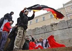 Manifestantes se preparan para quemar una bandera alemana y otra nazi en Atenas. / Foto: Reuters | Vídeo: Atlas